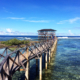 A scenic view of the Cloud 9 Boardwalk in Siargao, stretching over turquoise waters towards the famous surfing waves, with surfers and visitors enjoying the tropical paradise.