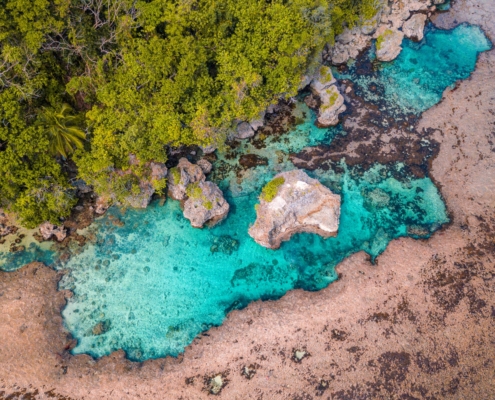 A stunning view of the Magpupungko Rock Pools in Siargao, with turquoise waters framed by jagged rocks, reflecting the clear blue sky.