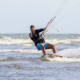 A kitesurfer skillfully riding the waves in Siargao, Philippines, against a backdrop of clear blue skies and the picturesque island scenery.